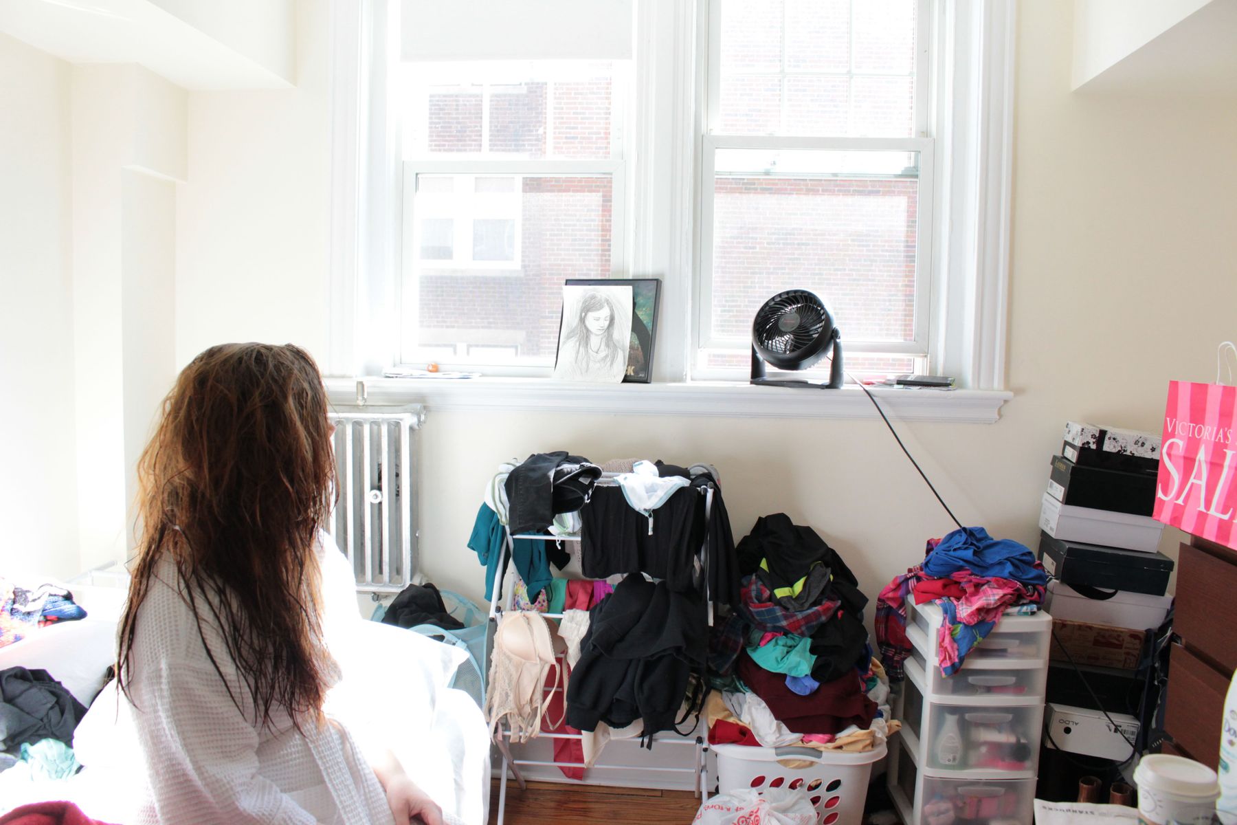 Megan, 24, faces toward the window of the apartment she will have to leave by August because she can no longer afford it. As she gets ready for work, her gaze falls on the sketch a stranger in a coffee shop had drawn of her when she was still a student at Boston University, before her anxiety had forced her to drop out of school. He captured her sadness perfectly, she says. 