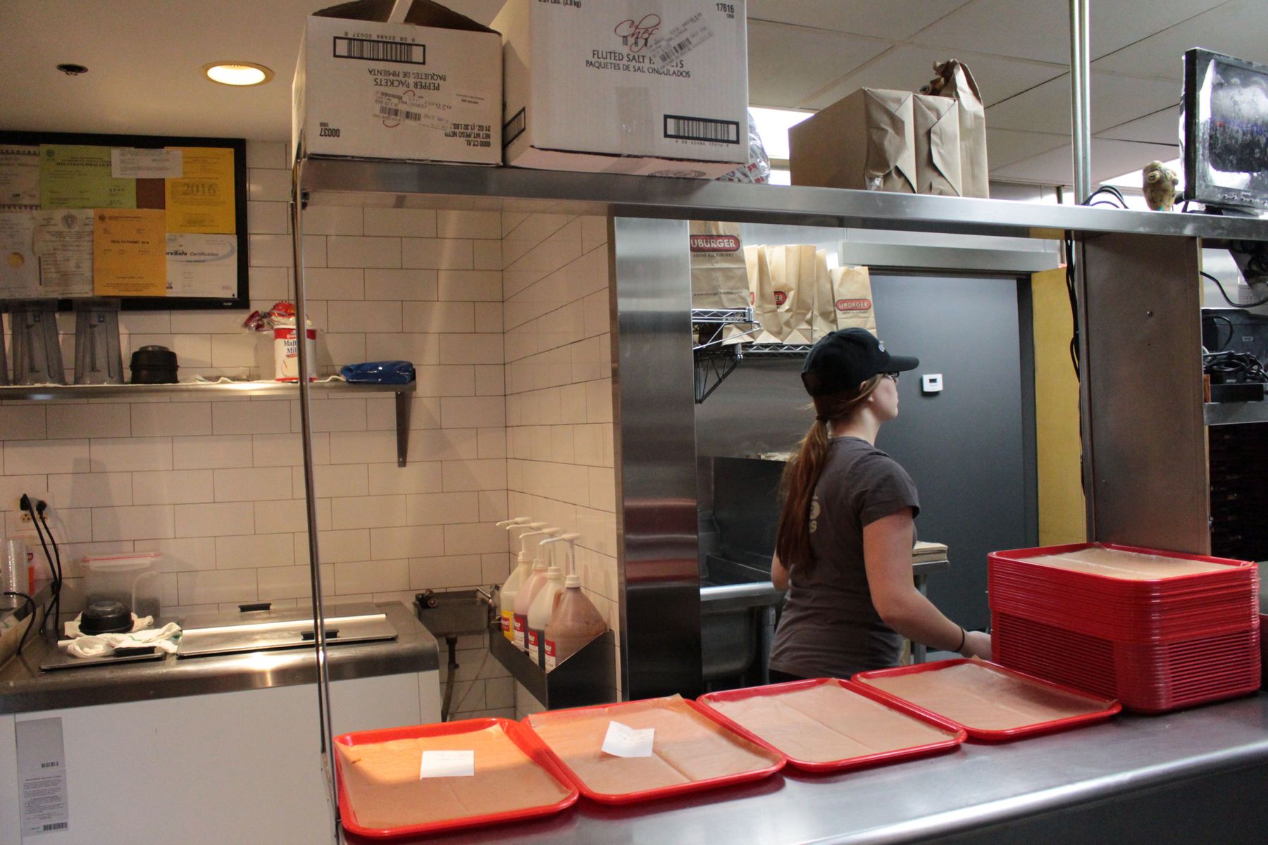 Megan makes measured movements in the tiny UBurger kitchen on a busy Saturday. She is “expoing,” as she says, or expediting—pulling tickets and filling orders—to help her new co-workers learn the ropes. 
